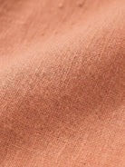 Close-up of soft peach-colored cotton fabric texture for lightweight cotton dress