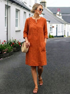 woman wearing rust-colored casual cotton dress with rolled 3/4 sleeves and pockets walking outdoors