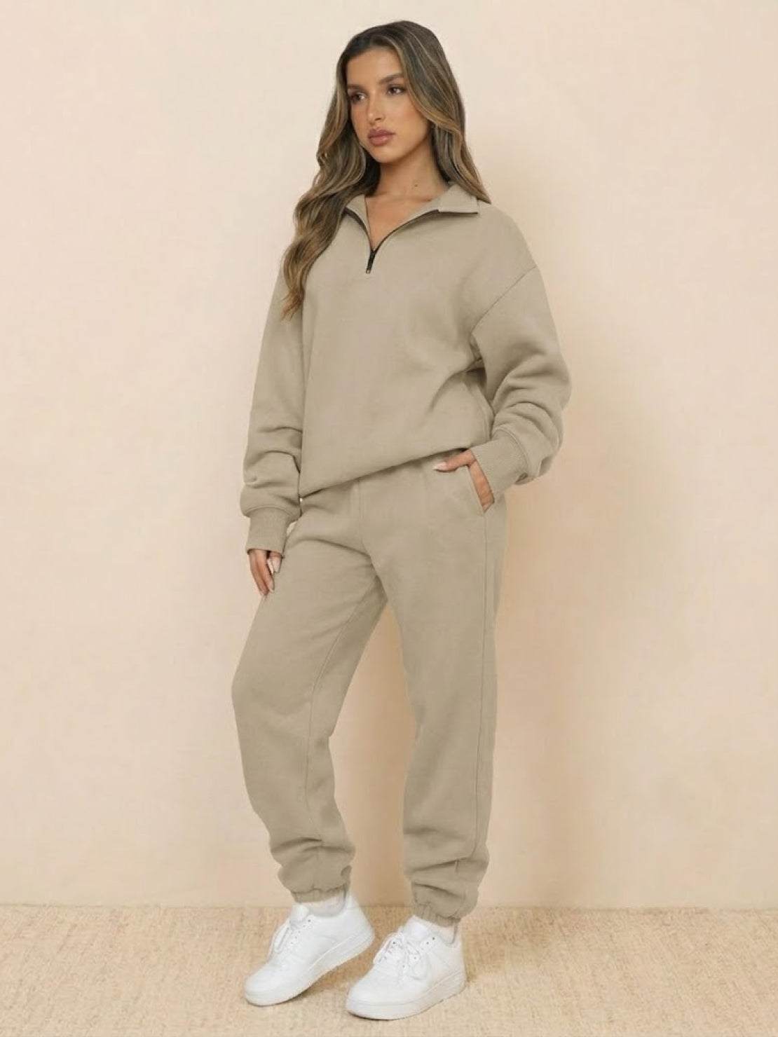 Woman wearing ultra-soft and comfy co-ord tracksuit set in khaki with white sneakers against a beige background