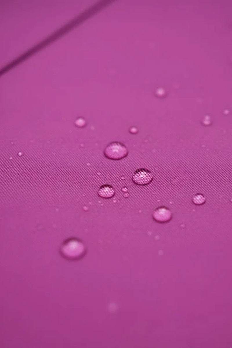 Close-up of water-repellent fabric with water droplets on purple surface for raincoat